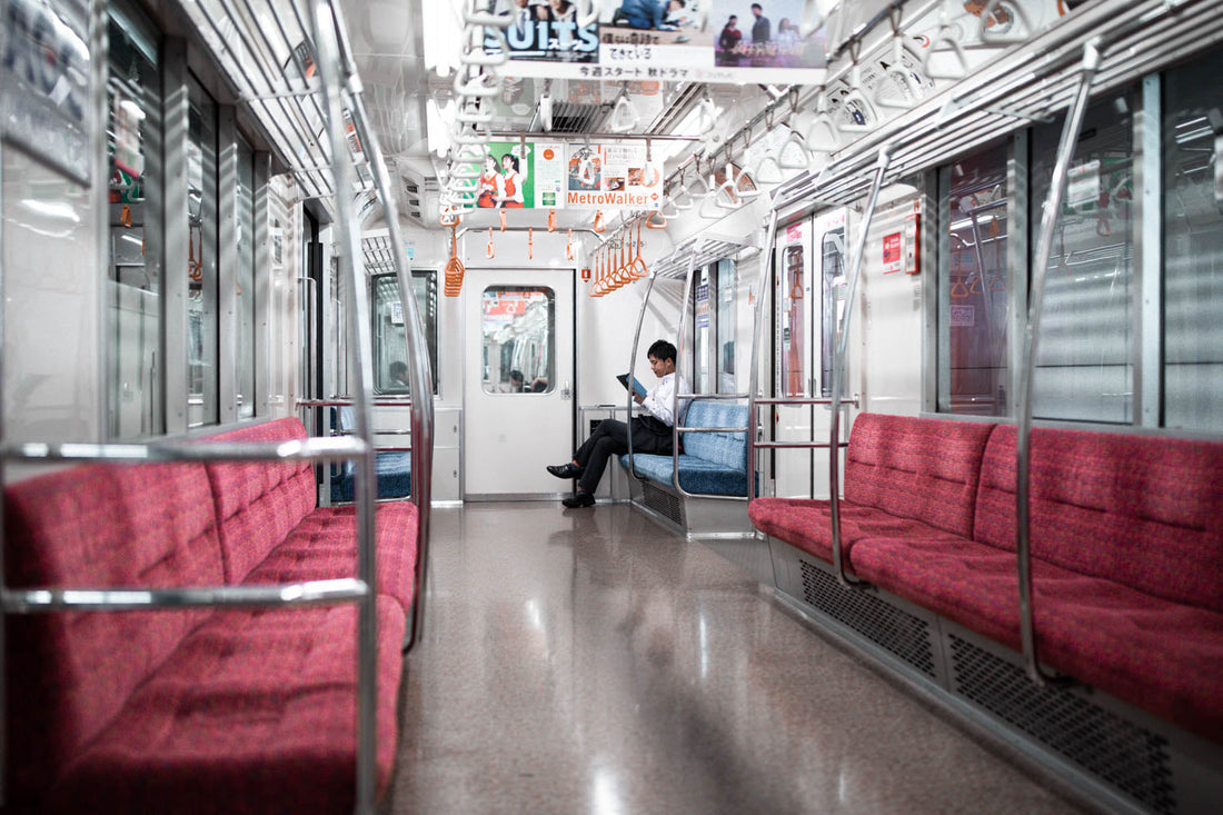 Man in business attire reading a book inside an empty subway train in Japan, capturing urban solitude and modern commuter lifestyle.