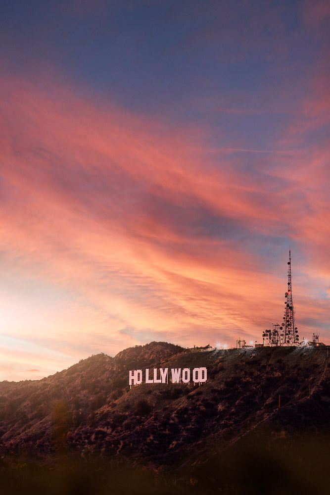 Iconic Hollywood Sign on the hills of Los Angeles, California, illuminated at sunset with a sky painted in vibrant pink and orange hues. A world-famous landmark symbolizing the entertainment industry.